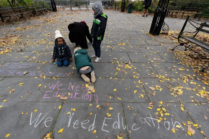 Students write graffiti on a sidewalk in front of City Hall during a protest by parents and students opposing the closing of schools.